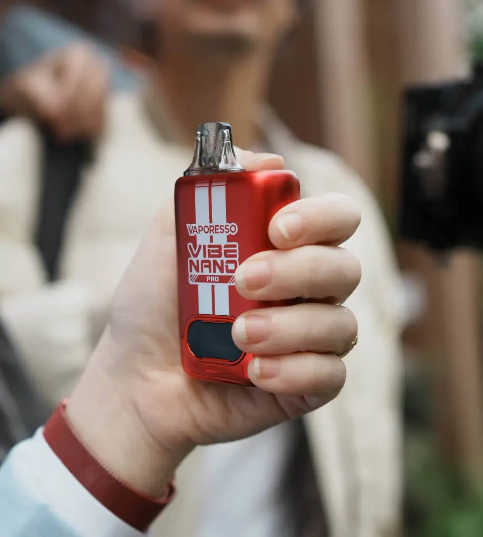 A person holding the red VAPORESSO VIBE NANO PRO, an ideal vape starter kit for active users. This open pod system vape is compact and perfect for beginners.